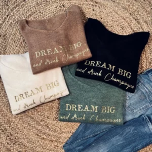 Collection de pull noir, blanc, kaki et camel avec slogan "Dream Big and drink Champagne" en or pailleté