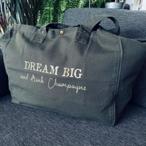 Sac fourre-tout kaki avec slogan "Dream Big and drink Champagne" en doré pailleté.