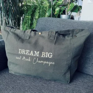 Sac fourre-tout kaki avec slogan "Dream Big and drink Champagne" en doré pailleté.