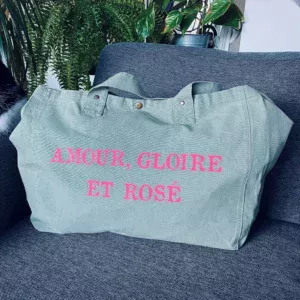 Sac fourre-tout vert sauge avec slogan "Amour, Gloire et rosé" en rose fluo.