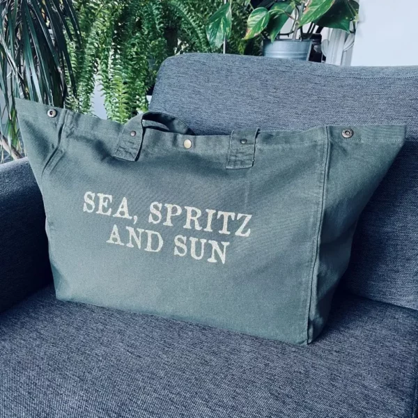 Sac fourre-tout kaki avec slogan "Sea, Spritz and Sun" en or pailleté.