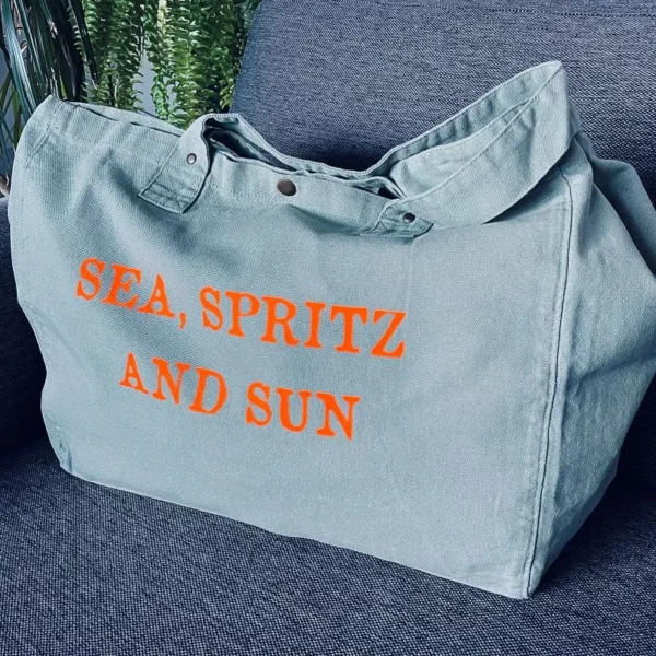 Sac fourre-tout vert sauge avec slogan "Sea, Spritz and Sun" en orange fluo.