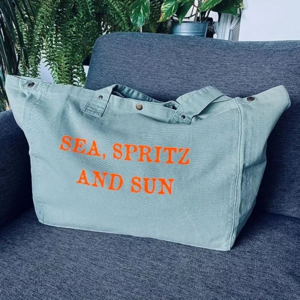 Sac fourre-tout vert sauge avec slogan "Sea, Spritz and Sun" en orange fluo.