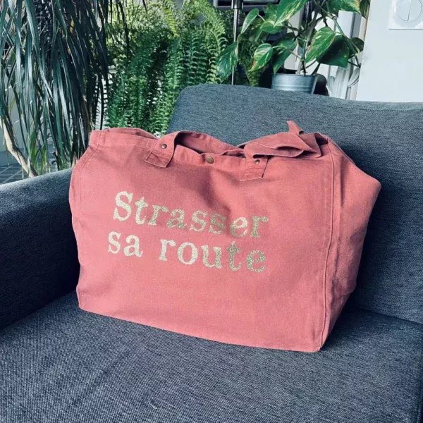 Sac fourre-tout vieux rose avec slogan "Strasser sa route" en doré pailleté.