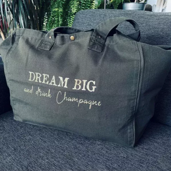 Sac fourre-tout kaki avec slogan "Dream Big and drink Champagne" en doré pailleté.
