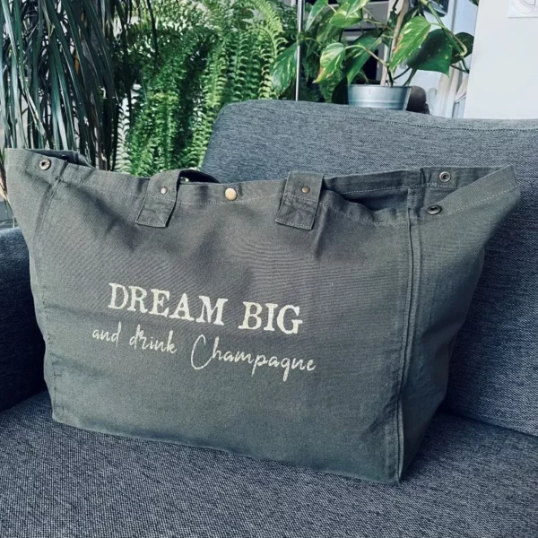 Sac fourre-tout kaki avec slogan "Dream Big and drink Champagne" en doré pailleté.