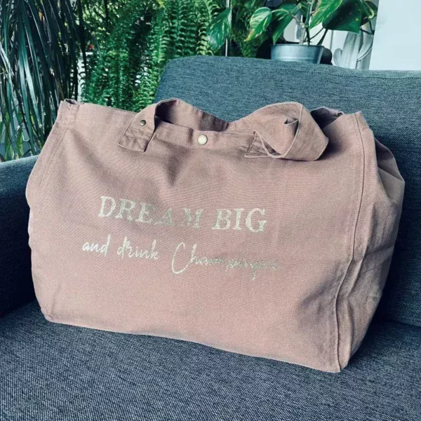 Sac fourre-tout coloris santal avec slogan "Dream Big and drink Champagne " en doré pailleté.
