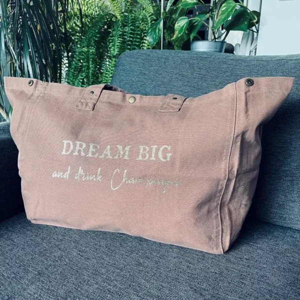 Sac fourre-tout coloris santal avec slogan "Dream Big and drink Champagne " en doré pailleté.