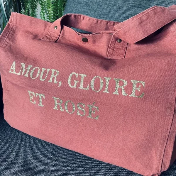 Sac fourre-tout vieux rose avec slogan "Amour, Gloire et rosé" en or pailleté.