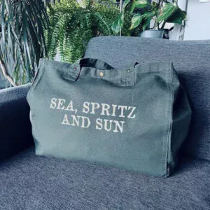 Sac fourre-tout kaki avec slogan "Sea, Spritz and Sun" en or pailleté.