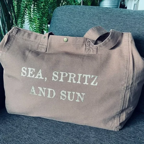 Sac fourre-tout santal avec slogan "Sea, Spritz and Sun" en or pailleté.