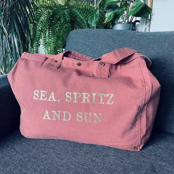 Sac fourre-tout vieux rose avec slogan "Sea, Spritz and Sun" en or pailleté.