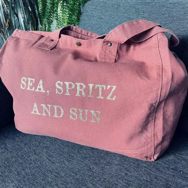 Sac fourre-tout vieux rose avec slogan "Sea, Spritz and Sun" en or pailleté.