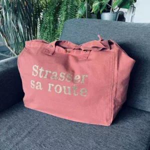 Sac fourre-tout vieux rose avec slogan "Strasser sa route" en doré pailleté.