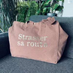 Sac fourre-tout coloris santal avec slogan "Strasser sa route" en doré pailleté.