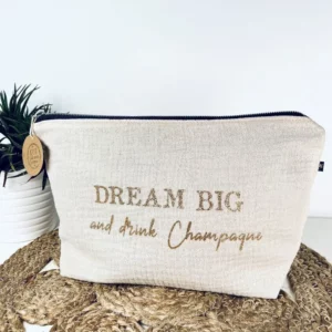 Trousse de toilette en gaze de coton blanc avec slogan "Dream big and drink Chamapgne" en or pailleté.