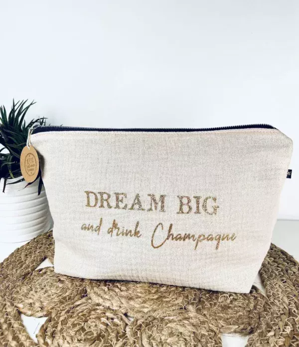 Trousse de toilette en gaze de coton blanc avec slogan "Dream big and drink Chamapgne" en or pailleté.