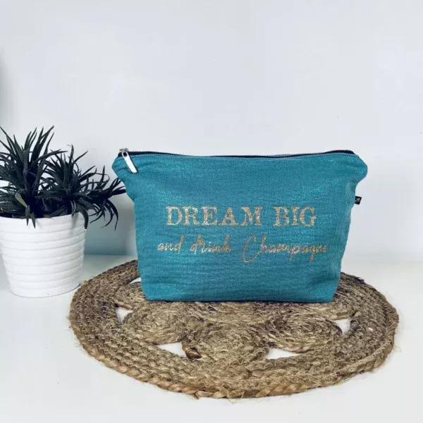 Trousse de toilette en gaze de coton bleu avec slogan "Dream big and drink Chamapgne" en or pailleté.