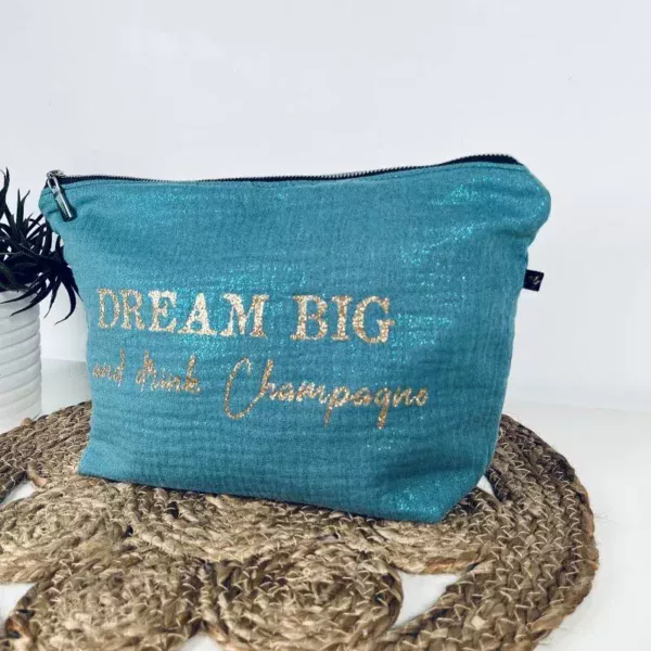 Trousse de toilette en gaze de coton bleu avec slogan "Dream big and drink Chamapgne" en or pailleté.