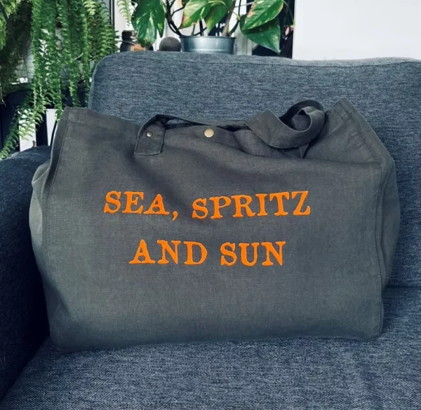 Sac fourre-tout kaki avec flocage "Sea, Spritz and Sun" en orange fluo.